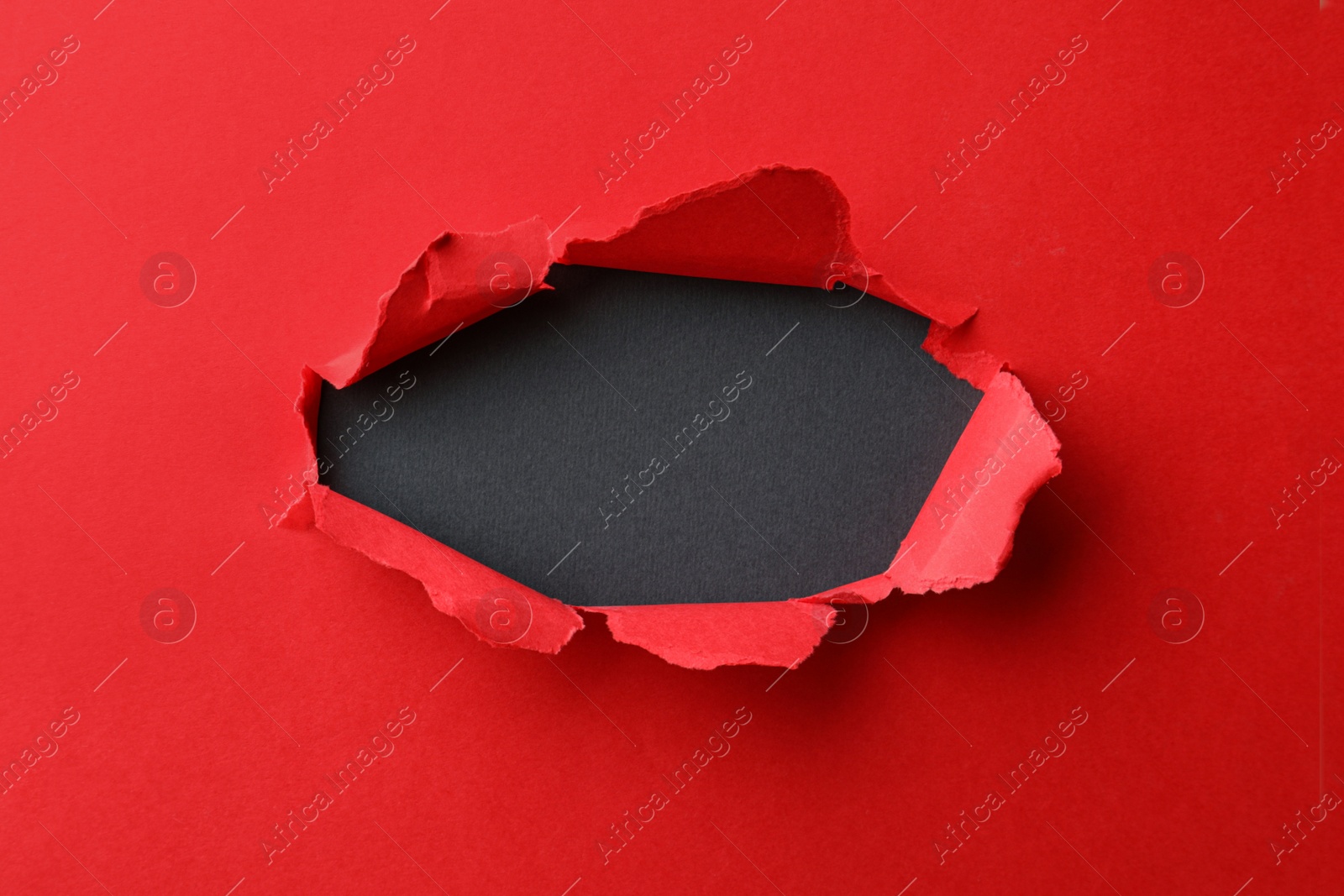 Photo of Hole in red paper on black background