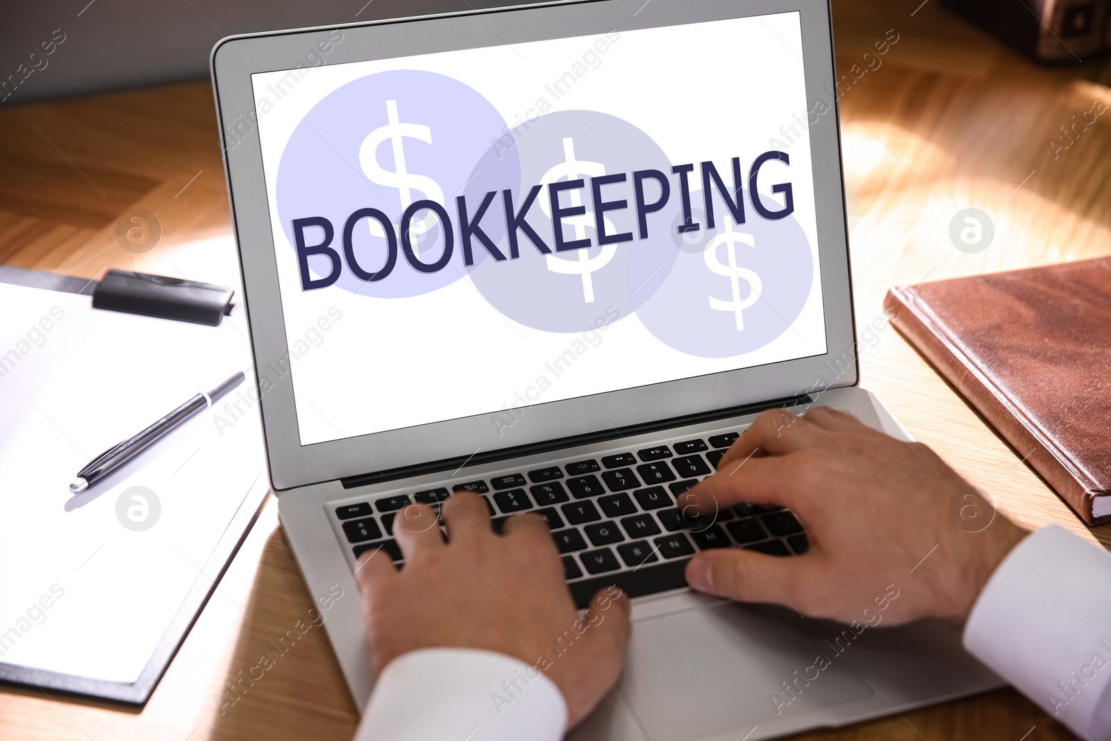 Image of Bookkeeping concept. Man working with laptop at wooden table, closeup
