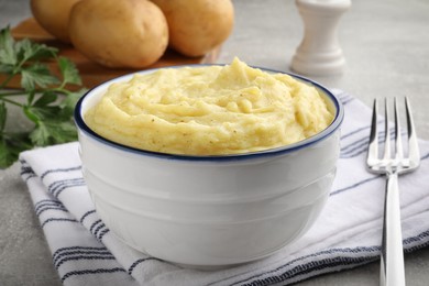 Photo of Bowl of tasty mashed potatoes served on grey table, closeup