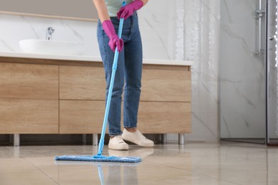 Woman cleaning floor with mop indoors, closeup. Space for text