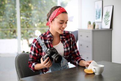 Photo of Young photographer taking picturecups at table indoors