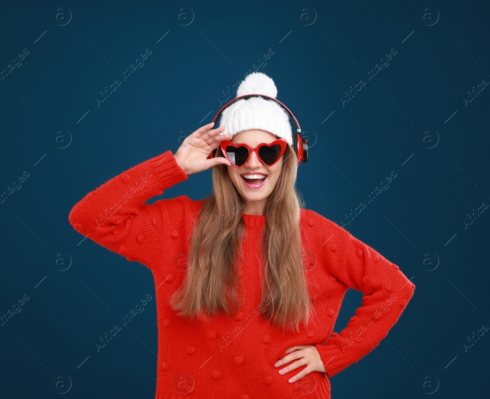 Photo of Young woman listening to music with headphones on dark blue background