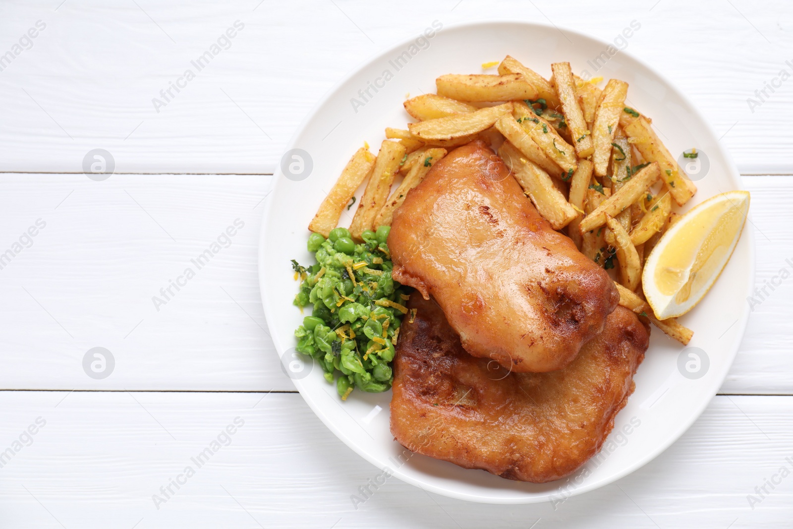 Photo of Tasty fish, chips, peas and lemon on white wooden table, top view