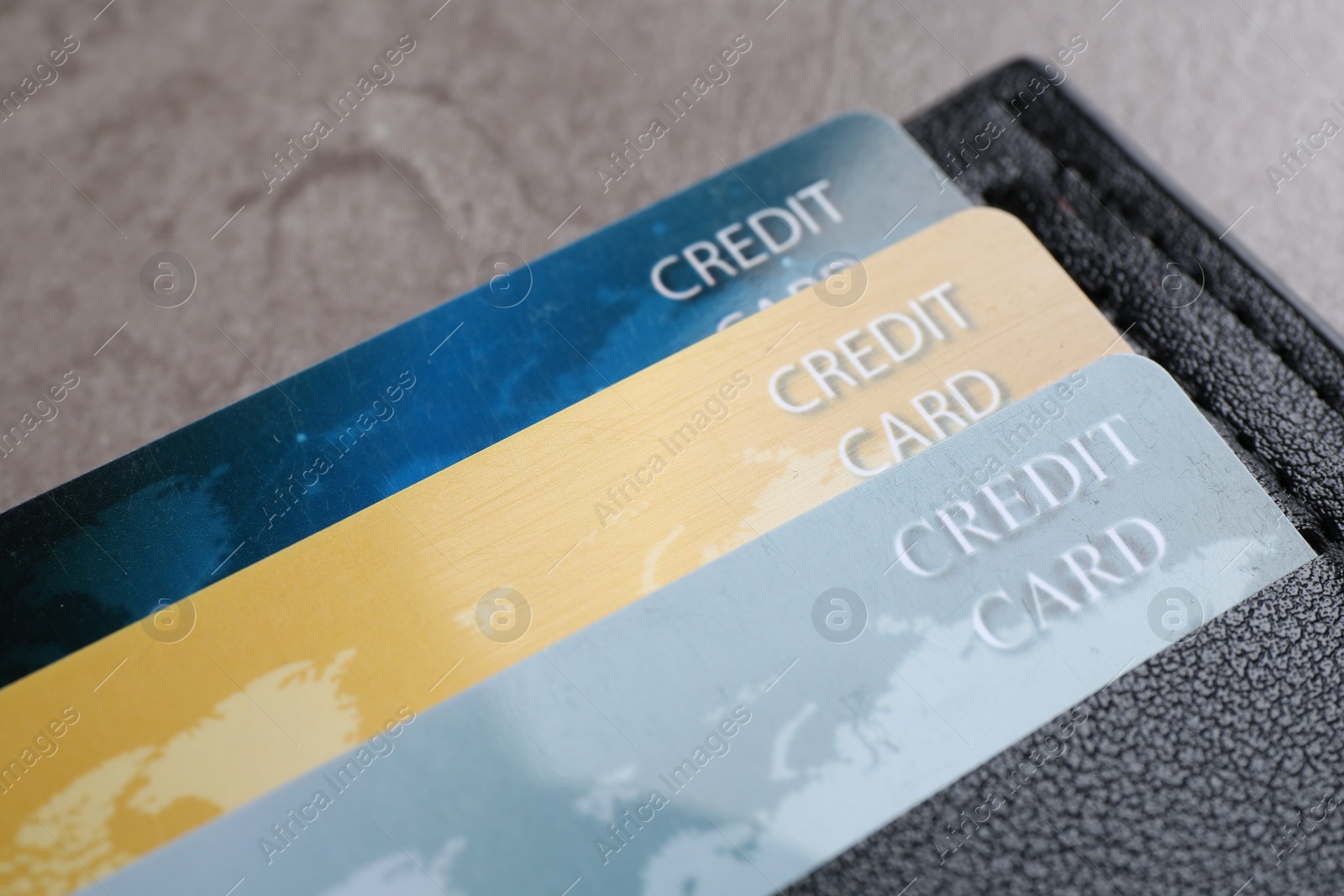 Photo of Credit cards in leather wallet on grey table, closeup