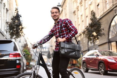 Handsome happy man with bicycle on city street