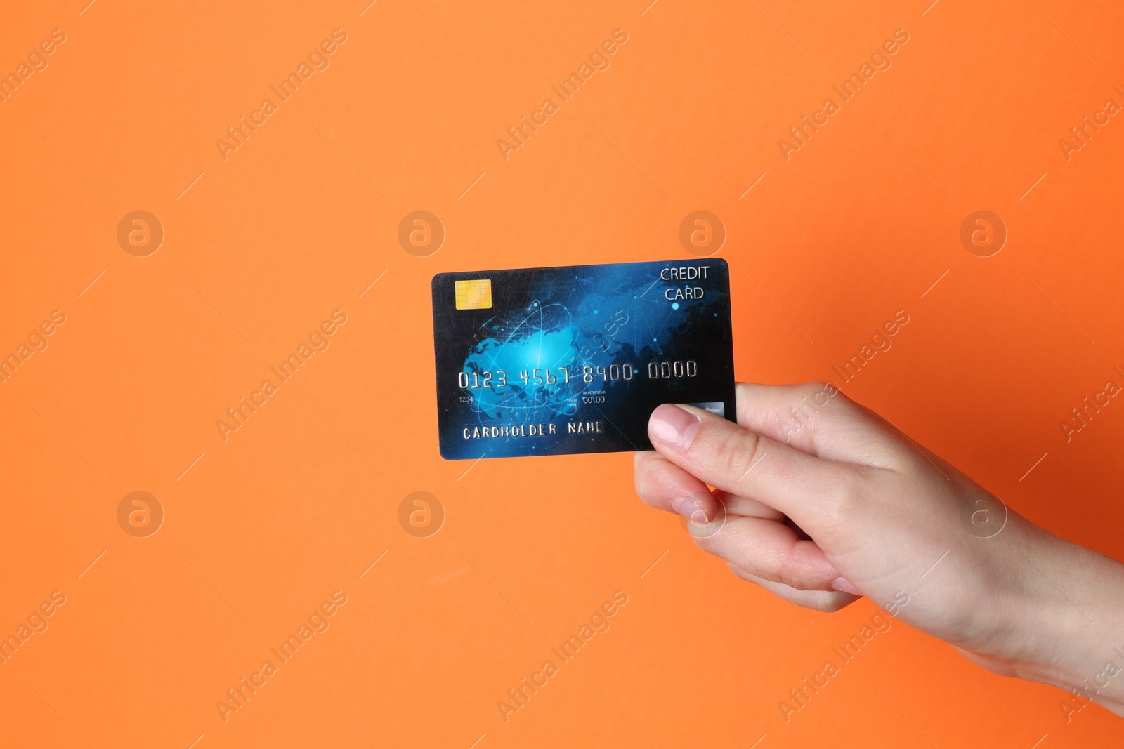 Photo of Woman holding credit card on orange background, closeup