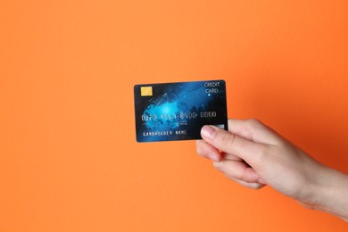 Photo of Woman holding credit card on orange background, closeup