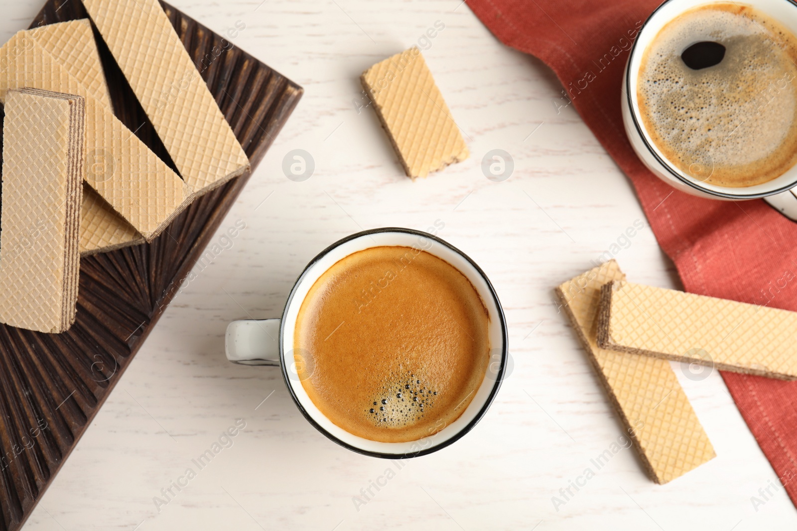 Photo of Delicious wafers and coffee for breakfast on white wooden table, flat lay