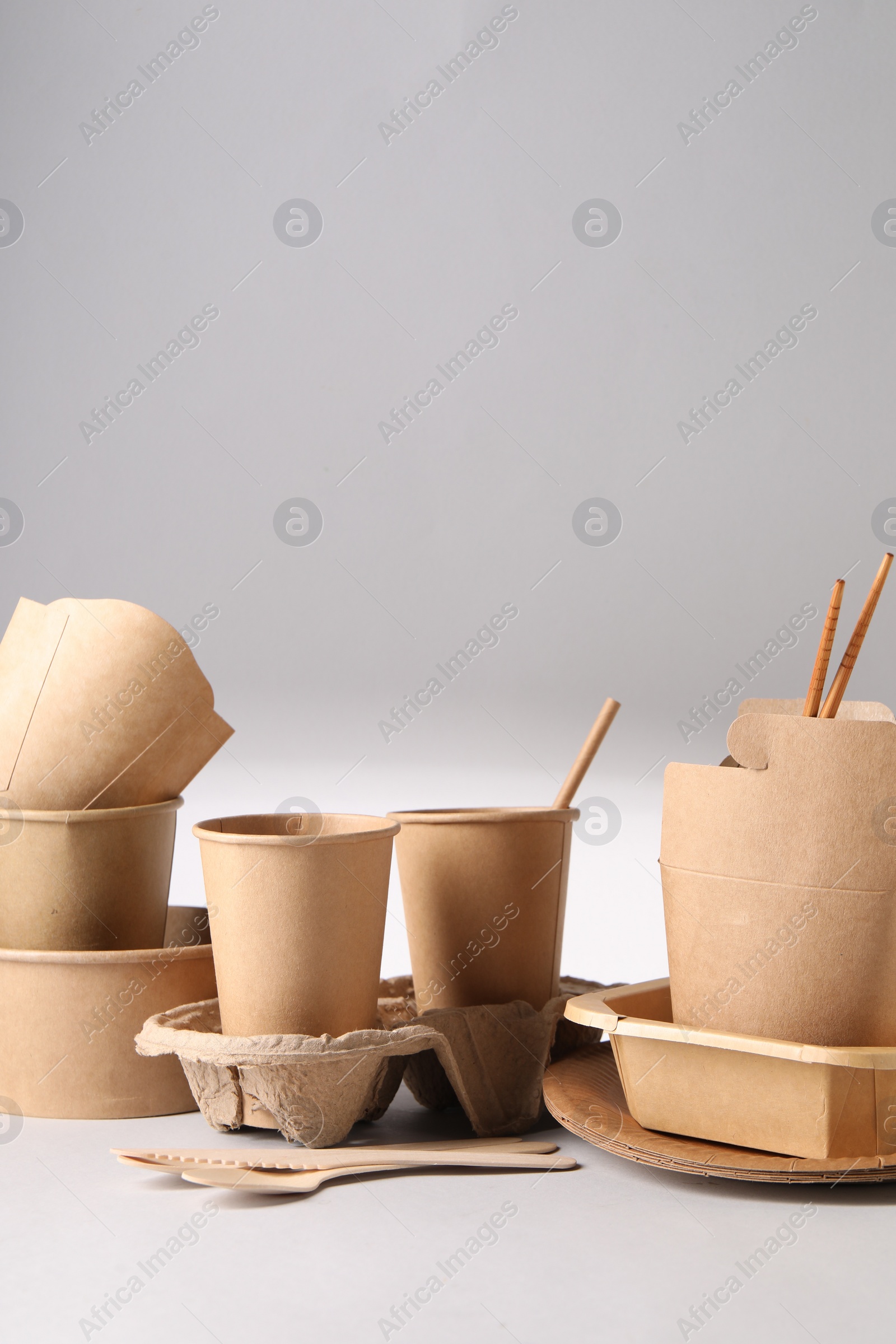 Photo of Eco friendly food packaging. Paper containers and tableware on light background