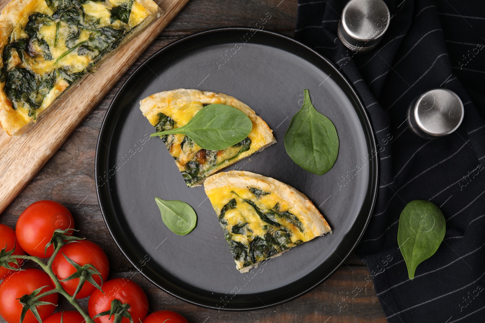 Photo of Pieces of delicious pie with spinach on wooden table, flat lay