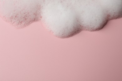 Photo of Fluffy soap foam on pink background, above view. Space for text