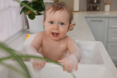 Photo of Cute little baby bathing in sink at home