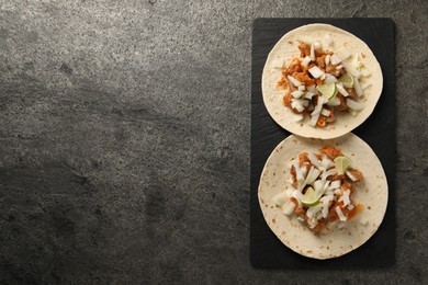 Photo of Delicious tacos with vegetables, meat and lime on grey textured table, top view. Space for text