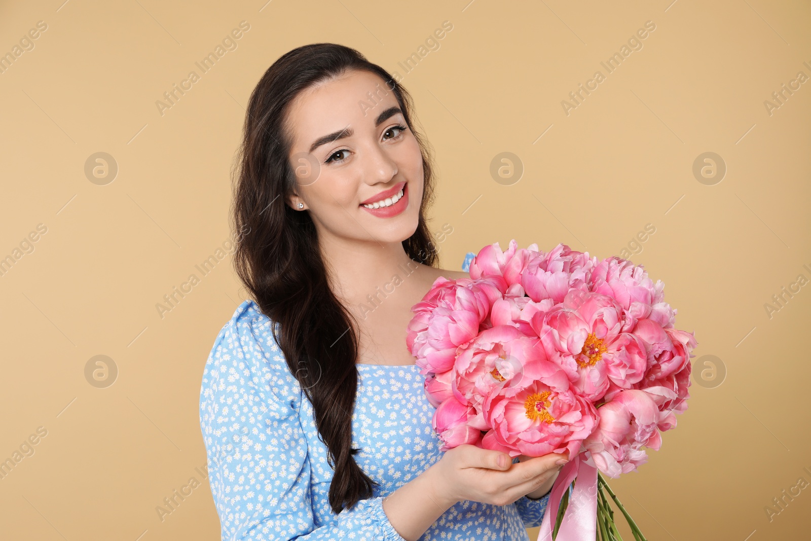 Photo of Beautiful young woman with bouquet of pink peonies on beige background