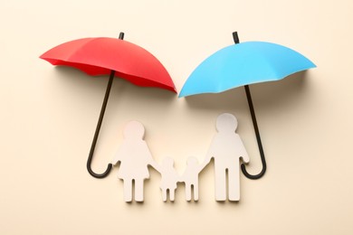 Photo of Mini umbrellas and family figure on beige background, flat lay
