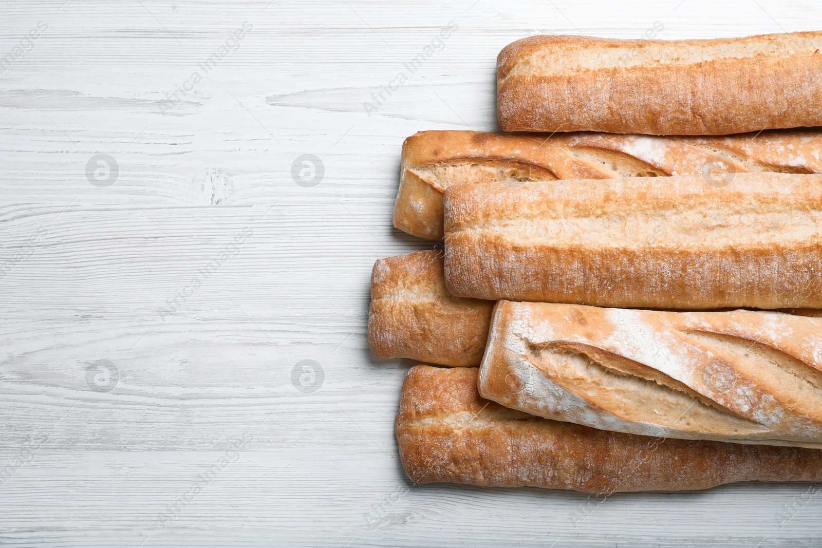 Photo of Tasty baguettes on white wooden table, flat lay. Space for text