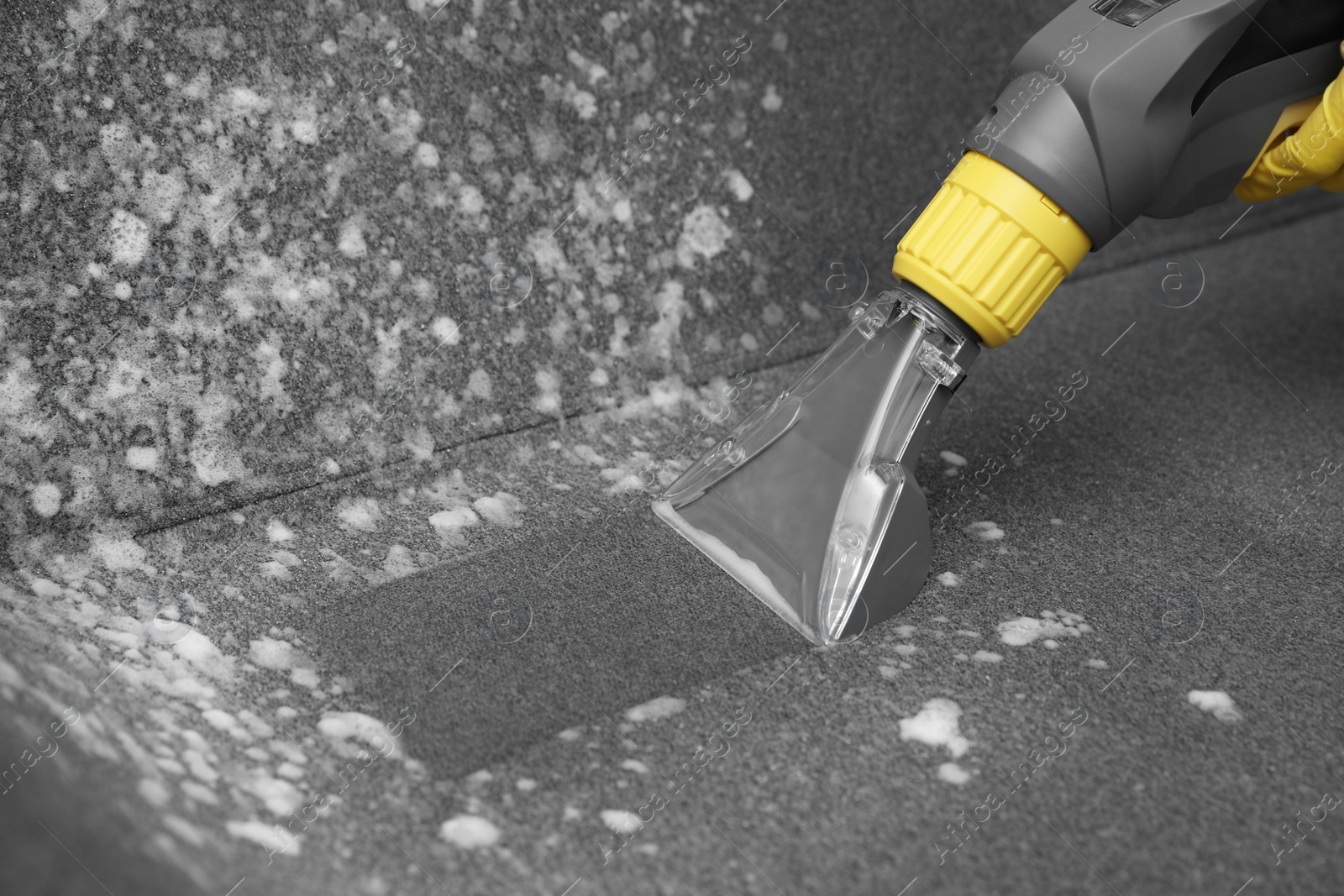 Photo of Janitor removing dirt from sofa with upholstery cleaner, closeup