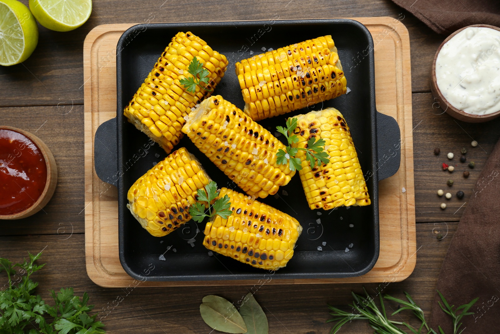 Photo of Flat lay composition with tasty grilled corn on wooden table