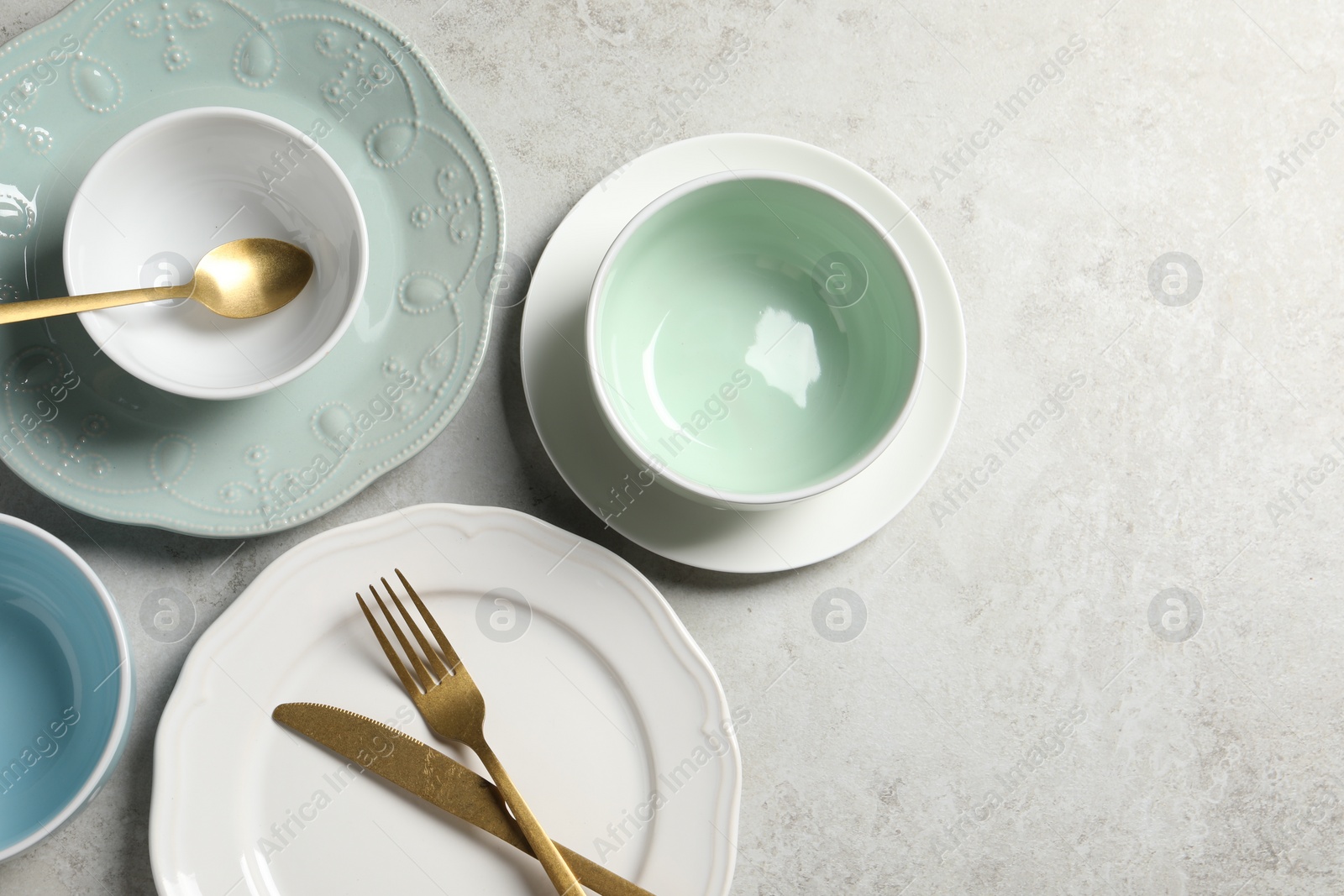 Photo of Beautiful ceramic dishware and cutlery on light grey table, flat lay. Space for text