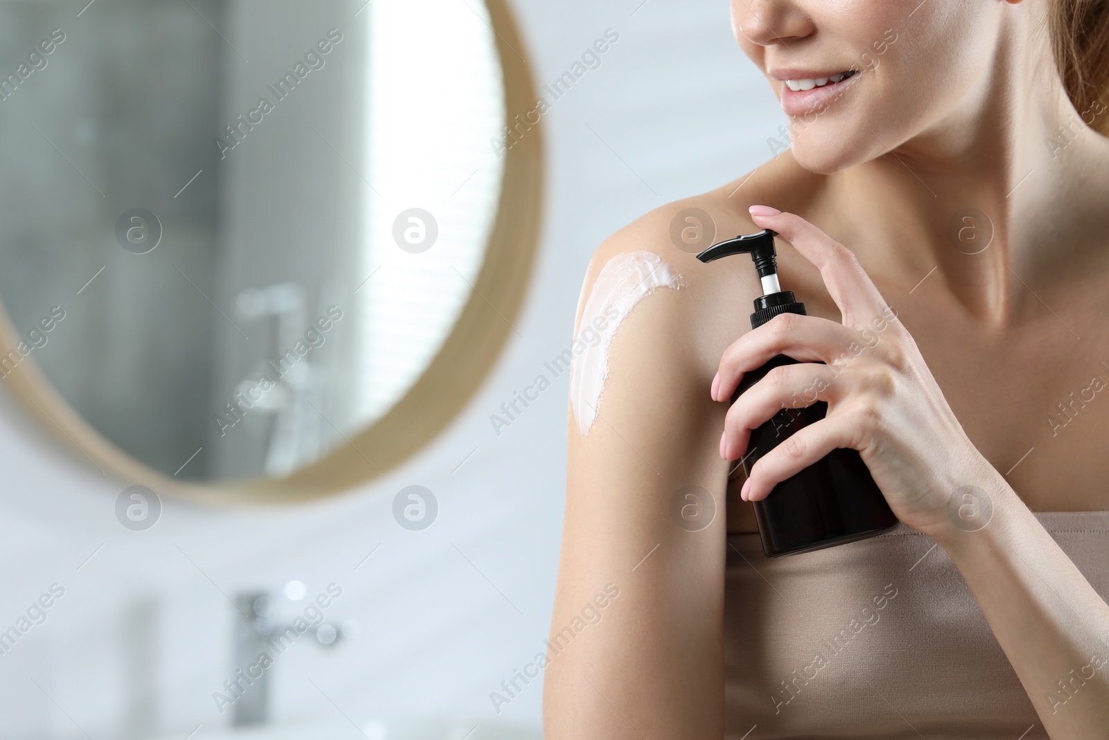 Photo of Woman applying body cream onto shoulder in bathroom, closeup. Space for text