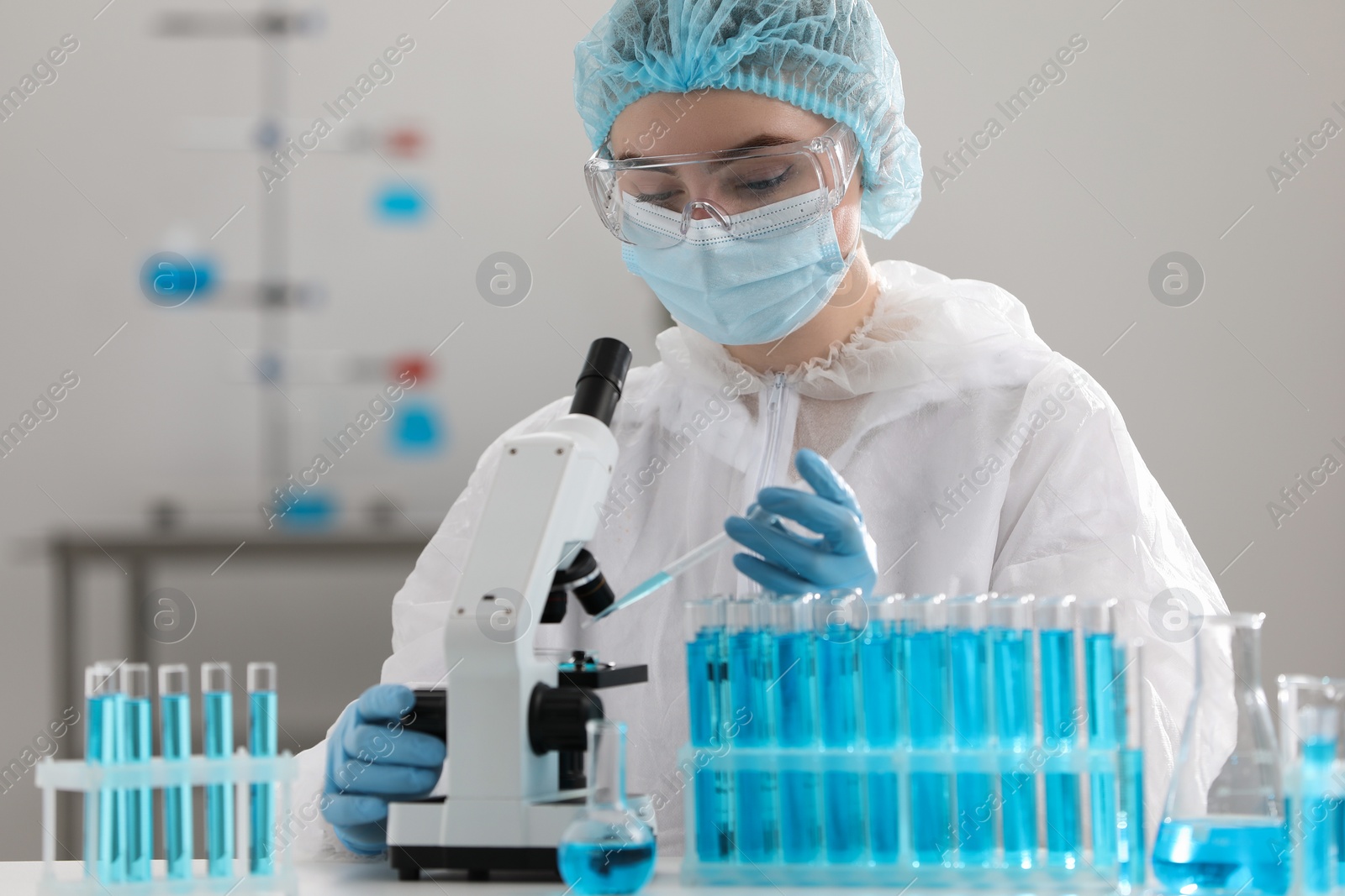 Photo of Scientist dripping sample onto Petri dish while working with microscope in laboratory.