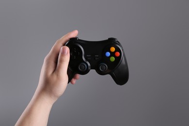 Photo of Woman holding wireless game controller on grey background, closeup