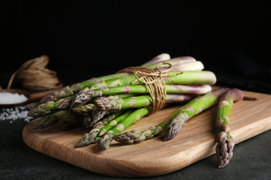 Photo of Fresh raw asparagus on black table, closeup