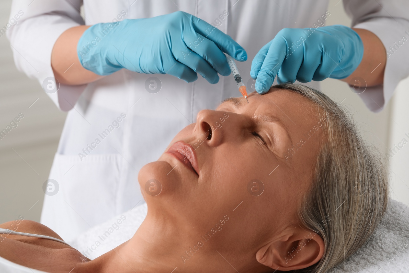 Photo of Doctor giving facial injection to senior woman in clinic, closeup. Cosmetic surgery