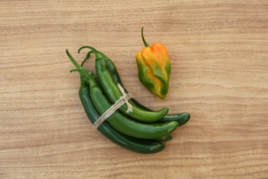 Photo of Different fresh ripe peppers on wooden table, flat lay