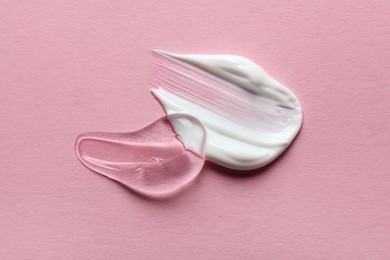 Samples of transparent gel and white cream on pink background, flat lay