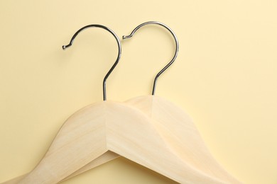 Photo of Wooden hangers on pale yellow background, flat lay