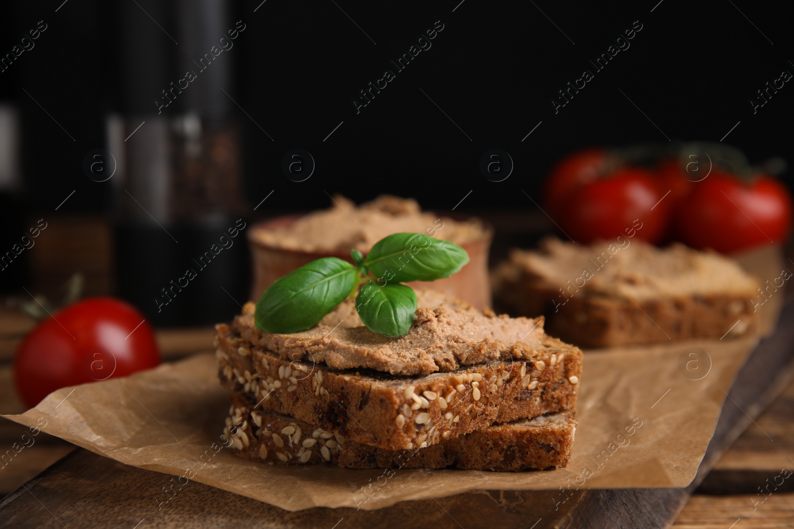 Photo of Fresh bread with delicious meat pate and basil served on wooden table, closeup