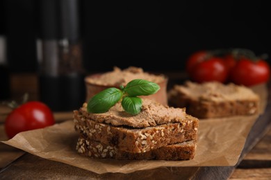 Photo of Fresh bread with delicious meat pate and basil served on wooden table, closeup