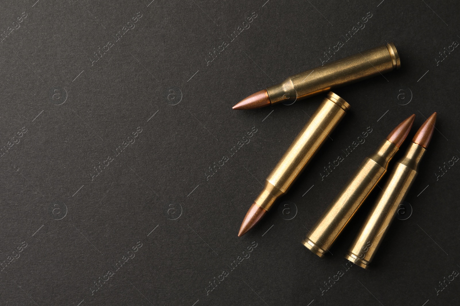 Photo of Bullets on black background, flat lay. Space for text