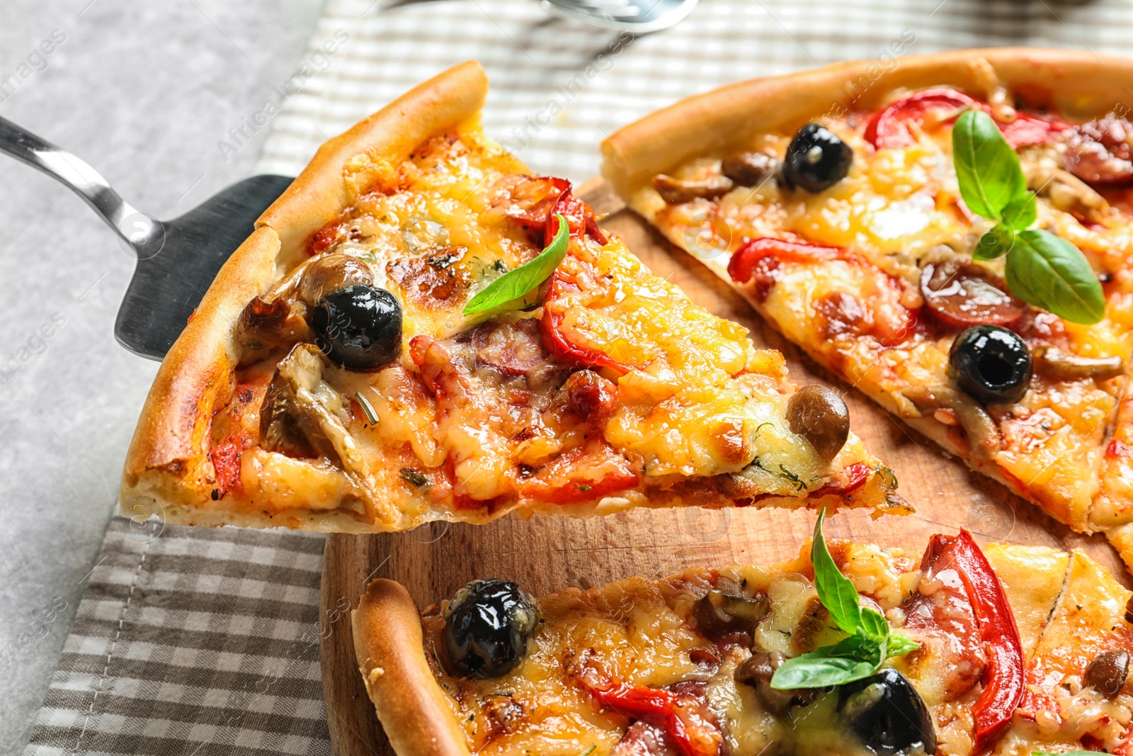 Photo of Slice of tasty pizza with olives and sausages on shovel, closeup