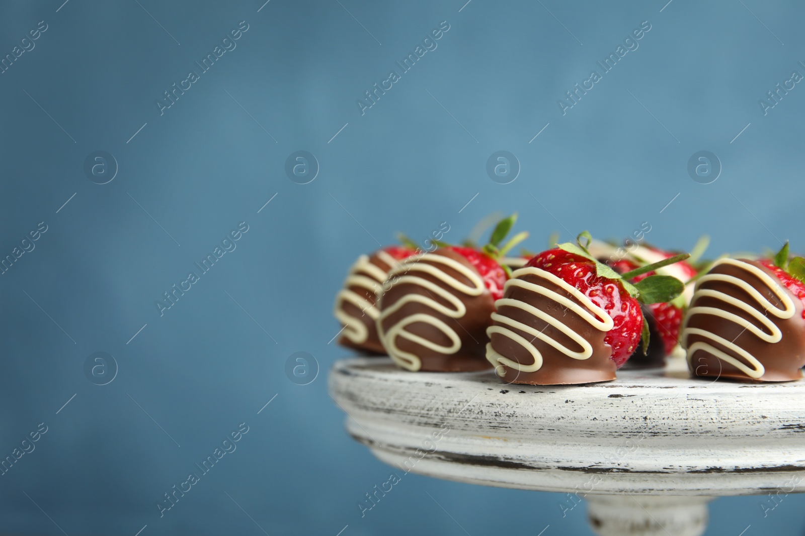 Photo of Dessert stand with chocolate covered strawberries on color background, closeup