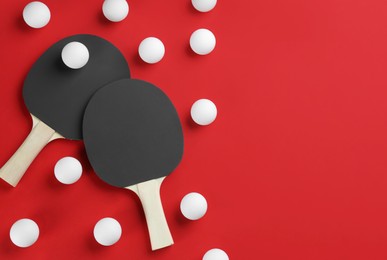 Ping pong rackets and balls on red background, flat lay. Space for text