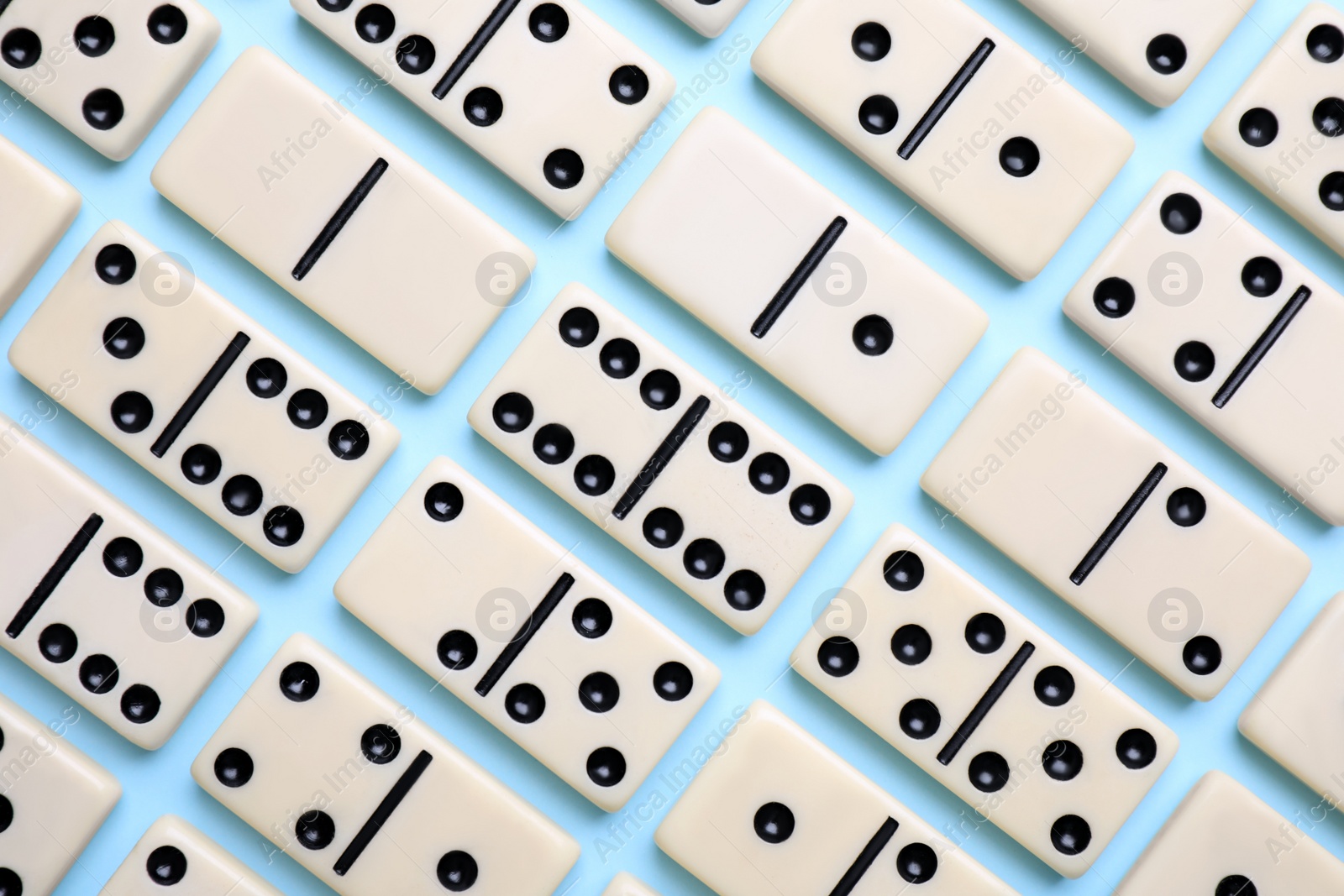 Photo of Classic domino tiles on light blue background, flat lay