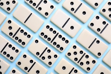 Photo of Classic domino tiles on light blue background, flat lay