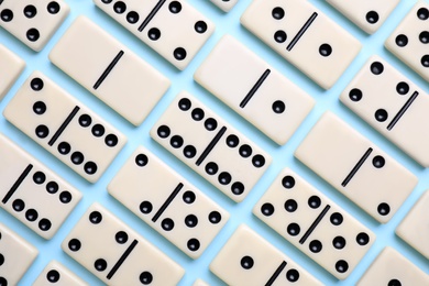 Classic domino tiles on light blue background, flat lay