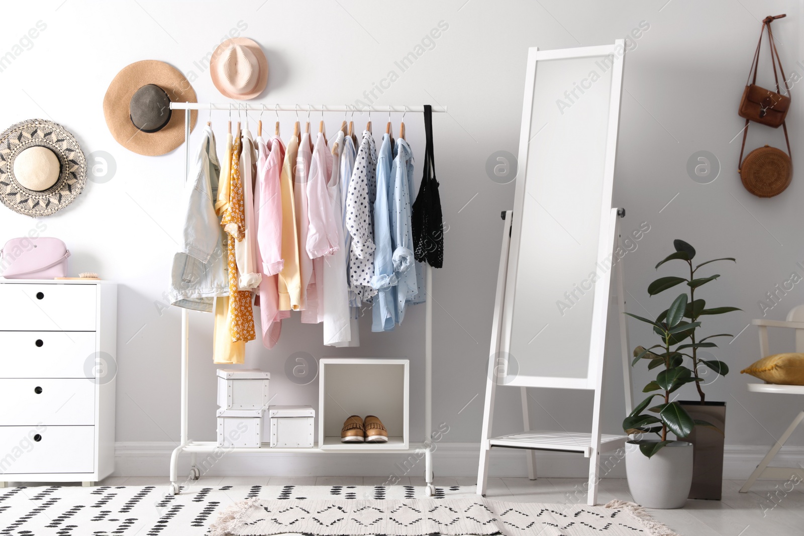 Photo of Rack with stylish women's clothes and mirror indoors. Interior design