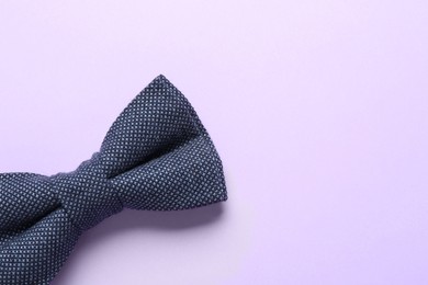 Stylish bow tie on lilac background, top view. Space for text