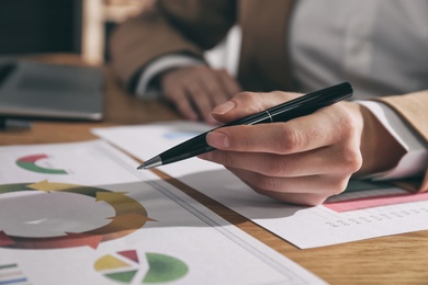 Photo of Businesswoman working with charts and graphs at table in office, closeup. Investment analysis