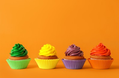 Group of different delicious cupcakes on orange background