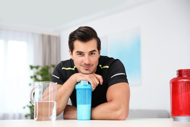 Photo of Young athletic man with protein shake at home