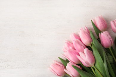 Beautiful pink spring tulips on white wooden background, flat lay. Space for text
