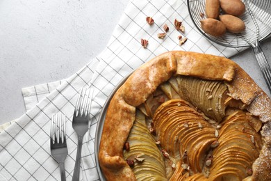 Photo of Delicious apple galette with nuts served on light grey textured table, flat lay