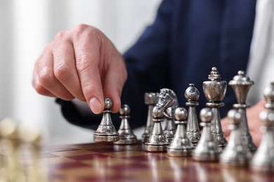 Man with game piece playing chess at checkerboard, closeup