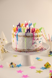 Photo of Tasty Birthday cake with burning candles and party decor on white table