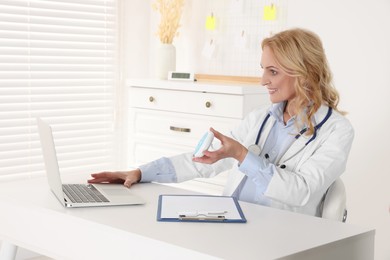 Photo of Doctor with laptop and pills consulting patient in clinic. Online medicine concept